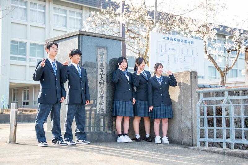 新制服を着て大野高校正門前で記念写真を撮る生徒たち