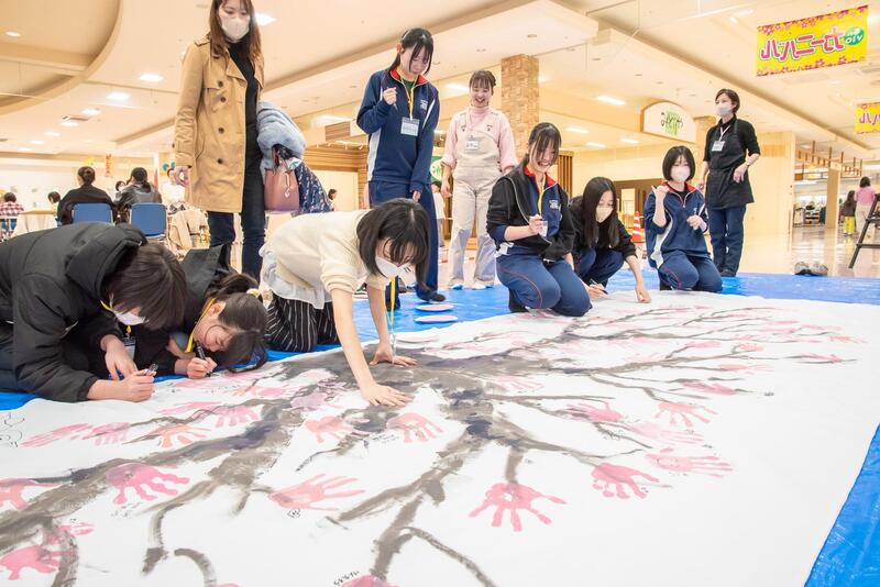 手形で桜のアートを作る高校生たち