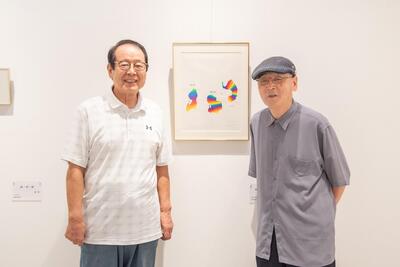 靉嘔の作品の前に立つ石田俊夫さんと山崎義昭さん