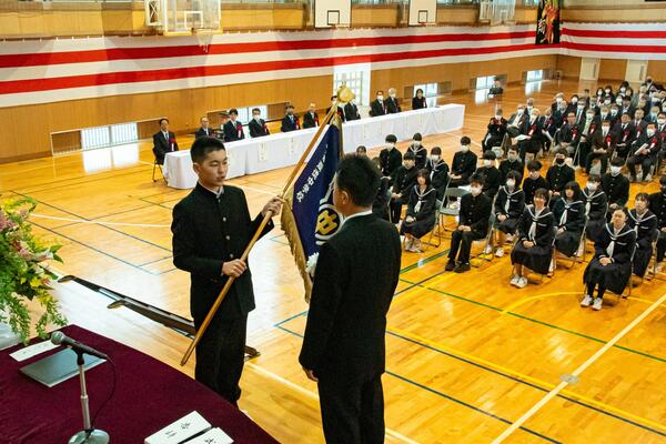 尚徳中学校閉校記念式典で学校旗を教育長に返還する生徒