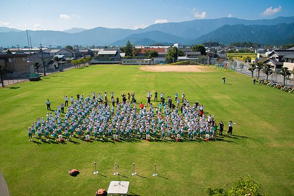 芝生化した有終南小学校の校庭に集まる児童や関係者